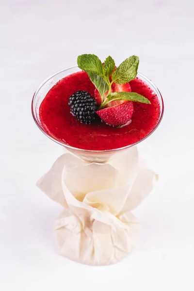 European dessert, national cuisine. Cream mousse under the jelly of red strawberries, raspberries, served with currants, mint and strawberries in a glass