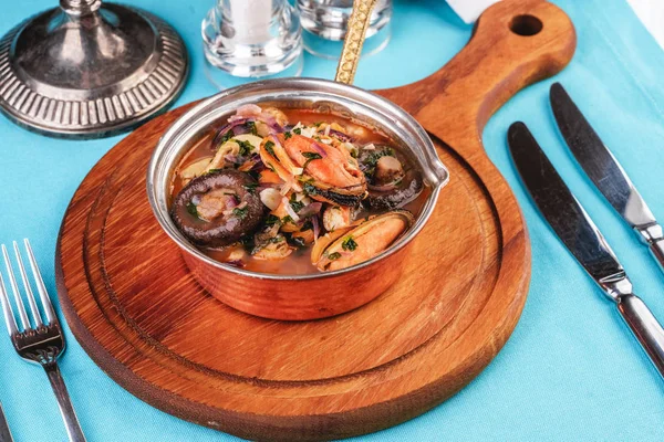European cuisine, Italian cuisine, Mediterranean dish. Minestrone stew soup with mushrooms, fish meat, squids, mussels, greens, tomatoes and shrimps