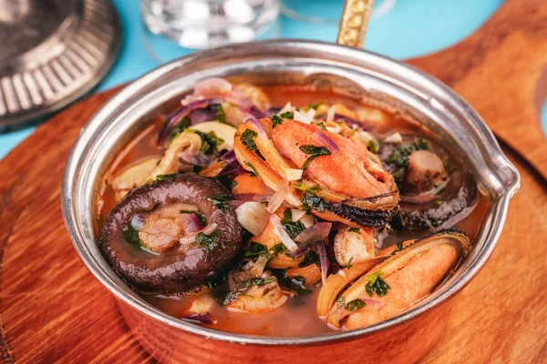 European cuisine, Italian cuisine, Mediterranean dish. Minestrone stew soup with mushrooms, fish meat, squids, mussels, greens, tomatoes and shrimps