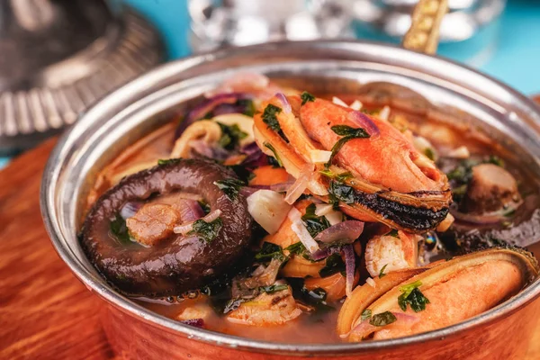 European cuisine, Italian cuisine, Mediterranean dish. Minestrone stew soup with mushrooms, fish meat, squids, mussels, greens, tomatoes and shrimps