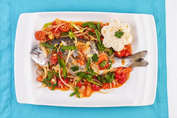 Seafood, Mediterranean cuisine. Baked sea fish with mushrooms, herbs, carrots, millers, cilantro, corn and onions. Caucasian national cuisine