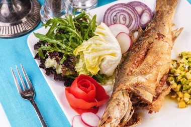 Gürcü tarifine göre sebze, salata ve yeşillikile servis edilen kızarmış balık