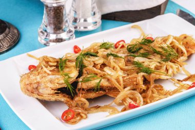 Kızarmış deniz balık turna levrek Gürcü tarifine göre soğan halkaları, biber ve yeşillik altında servis edilir. Akdeniz Mutfağı