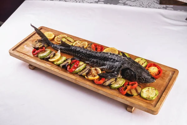 Seafood, Mediterranean cuisine. Baked sturgeon fish with grilled vegetables, tomatoes, lemon, zucchini and eggplants. Caucasian kitchen