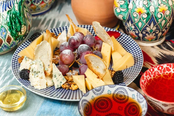 Cheese platter of brie, halumi, mozzarella, kachota, kokokovallo with grapes, berries and nuts for wine in an oriental style.