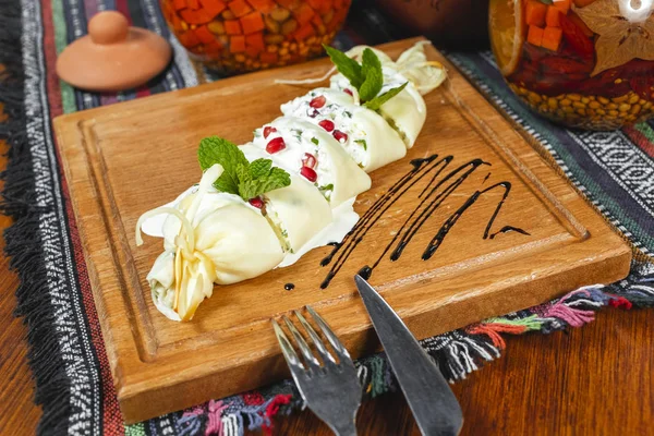 Traditional Georgian cuisine, national food. Creamy cheese roll, greens, served with balsamic sauce and pomegranate seeds