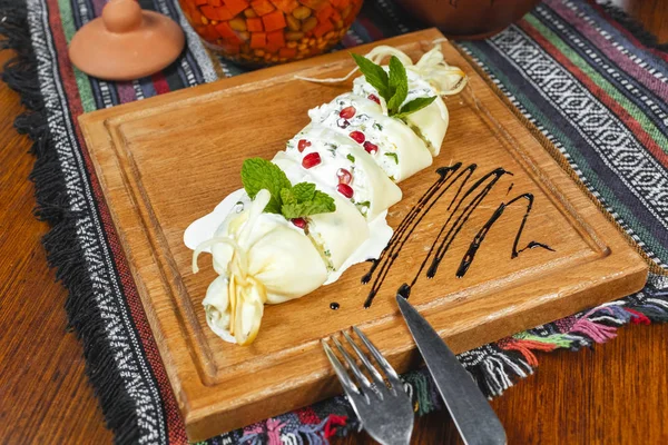 Traditional Georgian cuisine, national food. Creamy cheese roll, greens, served with balsamic sauce and pomegranate seeds