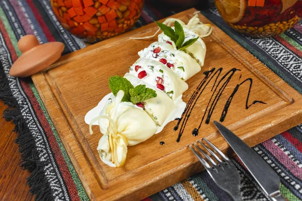 Traditional Georgian cuisine, national food. Creamy cheese roll, greens, served with balsamic sauce and pomegranate seeds