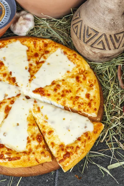 Georgian national dish with cheese, butter and herbs - khachapuri. Baked diced dough with spices and cheese, appetizer in Georgian style. National cuisine