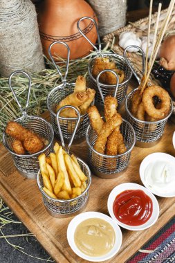 Oryantal tarzında şirket çeşitli aperatifler - soğan halkaları, şiş, patates kızartması, domates ve ekşi krema soslar bir dizi sosis