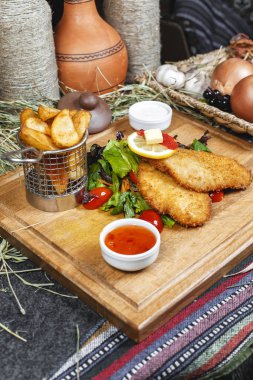 Balık meyilli tığ işi, patates rustik, yeşillik, kiraz domates, salatalık, domates ve krema sosları ile