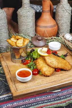 Balık meyilli tığ işi, patates rustik, yeşillik, kiraz domates, salatalık, domates ve krema sosları ile