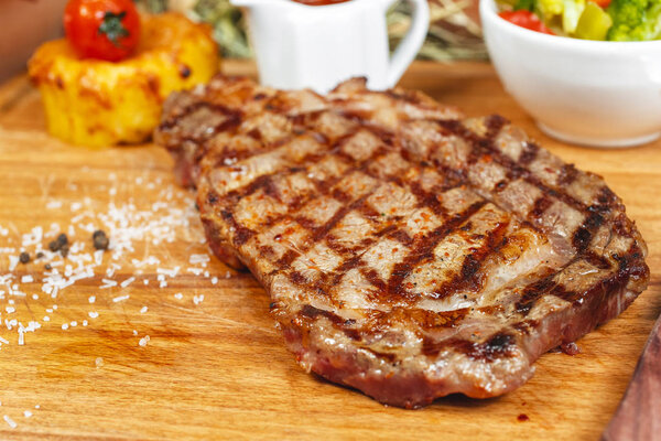 Grilled beef steak according to Georgian recipe. Served with tomato sauce and fresh vegetable salad. National cuisine