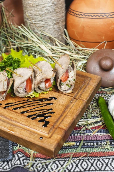 Meat rolls of horse meat with tomato and stuffing, with greens and tomatoes according to the Eastern recipe