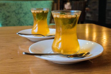 Küçük bardaklarda Türk narenciye çayı, çam fıstığı ve nane yaprakları nın eklenmesiyle. Avrupa tarifi