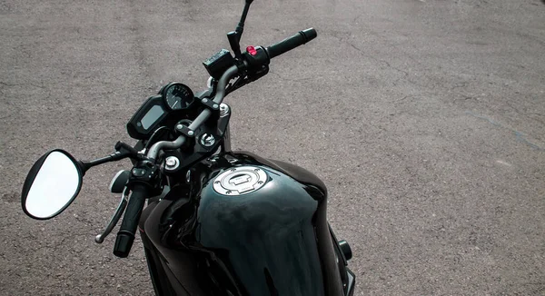 Elegante motocicleta brillante negro con un volante negro y espejos. Chopper estacionado sobre un fondo de asfalto gris . — Foto de Stock