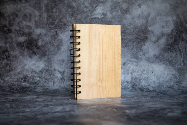 notepad with wooden cover on a gray background. side view, isolate