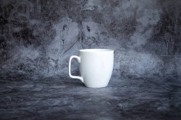 Biały kubek na kawę na ciemnym tle. widok z boku, izolacja — Zdjęcie stockowe