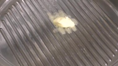 Tereyağı bir parça sıcak çelik ızgara Pan, bir bıçak, erime ve kabarcıklar ile smear düşer. Yakın çekim.