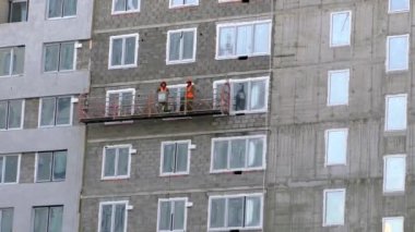 Tyumen, Rusya-19 Mart 2019. Endüstriyel dağcılık. Çalışanlar, inşaat altında çok katlı bir binanın duvarı boyunca aşağı doğru kalkar. Yakınlaştır.