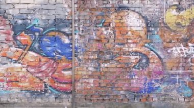 Yarı yıkanmış yazıtlar ve bilinmeyen sanatçının Graffiti ile boyanmış, düzensiz parçalanmış duvar ve yamalar ile çok pitoresk uzun eski tuğla duvar. İnsanlar olmadan (kimse).