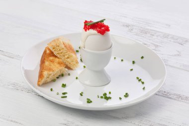 Creme fraiche, Lumpfish roe ve Frenk soğanı, toast ile beyaz tabakta ile süslenmiş beyaz bir yumurtalık içinde haşlanmış yumurta.