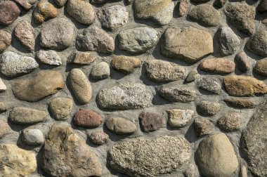 Çimento harcı ile sabitlenmiş taşlar. Çakıl taşlarından bir duvar. 