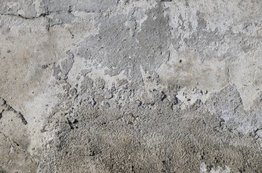 Alçılı bir duvara yakın çekim. Açık gri, pürüzlü ve çatlak duvar yüzeyi. 