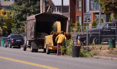 Banliyöde temizlik işe yarar. Bir işçi yonga makinesi kullanıyor.. 
