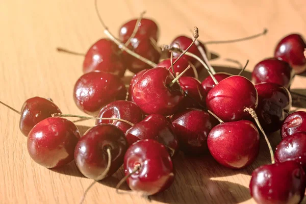 Sweet cherry (black cherry) lies in a group on a wooden table. Close-up