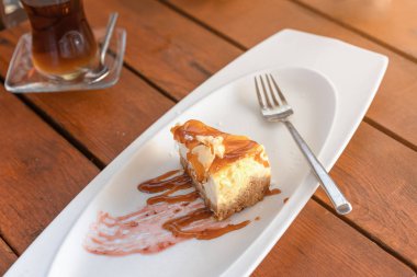 Beyaz bir tabak ve bardak çay ahşap bir masa üzerinde peynirli kek. hafif kahvaltı konsepti