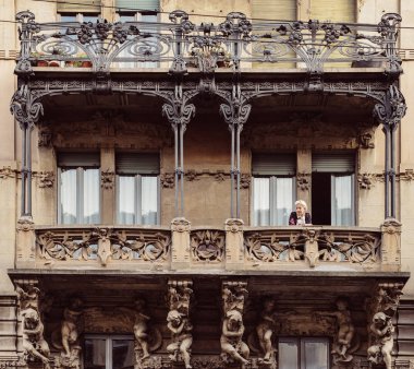 Milan, İtalya - 24 Mayıs 2018: Balkon tipik Konut Sarayı Porta Venezia mahalle, yaşlı kadın. 20. yüzyılın başlarında mimaridir doğa ilham Liberty, art-nouveau tarzı