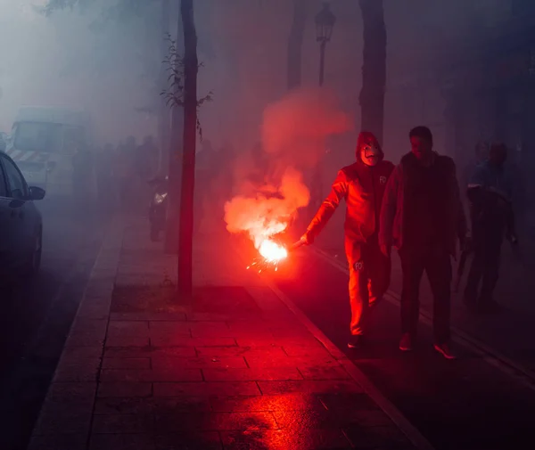 Paris, France - May 26, 2018: Protestors wearing a Guy Fawkes mask light gas canisters to express their anger against French President Macro's government, among other issues, on the streets of Paris