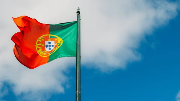 Piękny duży portugalski flaga macha na wietrze na niebieskim tle w Lizbona, Portugalia — Zdjęcie stockowe