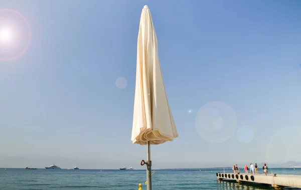 Пляжна парасолька з видом затоки, пристані і розкішні човни на узбережжі Середземного моря, Жан ле Пен, Франції — стокове фото