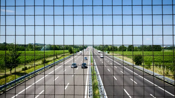 Imagem da cerca da ligação chain na ponte sobre a passagem. Cerca de corrente na ponte acima da estrada. Imagem industrial abstrata da cerca da ligação chain e carros na estrada . — Fotografia de Stock