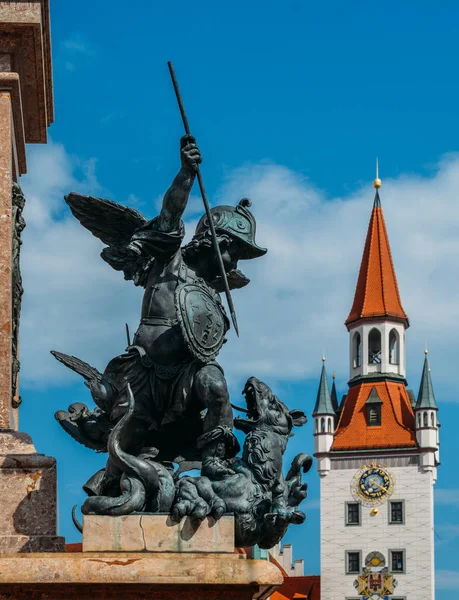Estatua de putto matando a un dragón en el pedestal de columnas marianas, Marienplatz con Spielzeugmuseum en el fondo — Foto de Stock