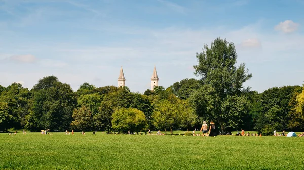 Skyline di Monaco di Baviera da Englischer Garten, Germania. La gente del posto e turisti godono di una calda giornata estiva nel parco — Foto Stock