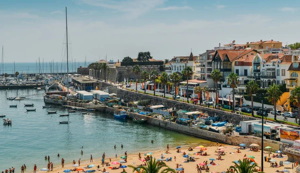 Ponto de vista alto de areia lotada Praia do Ribeiro e barcos na baía um dia ensolarado de verão. Cascais é uma pequena vila pitoresca a 30km a oeste de Lisboa — Fotografia de Stock