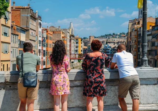 Familia de turistas con vistas a coloridas casas rojas y amarillas y puente río Onyar. Girona es un famoso destino turístico perfecto para vacaciones y vacaciones — Foto de Stock