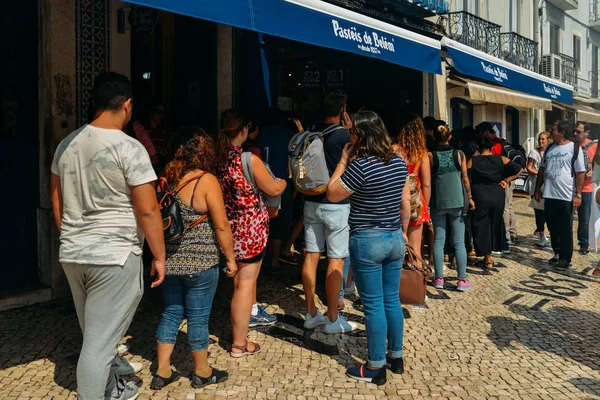 Люди стоят в очереди перед пекарней Pasteis de Belem в Лиссабоне, Португалия, где родился этот знаменитый португальский десерт под названием Pasteis de Nata — стоковое фото