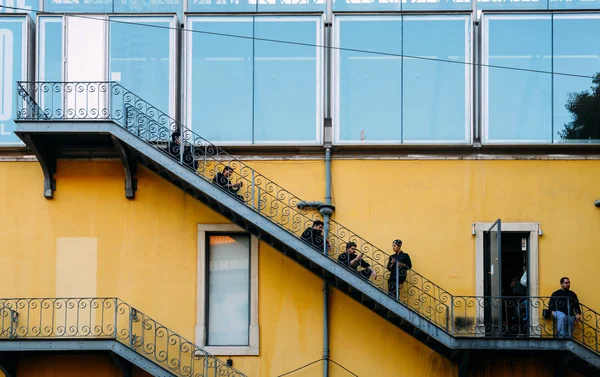 Arbeiter in Uniform checken ihre Smartphones und genießen eine Zigarettenpause auf einer klassischen Feuertreppe in Lissabon, Portugal — Stockfoto