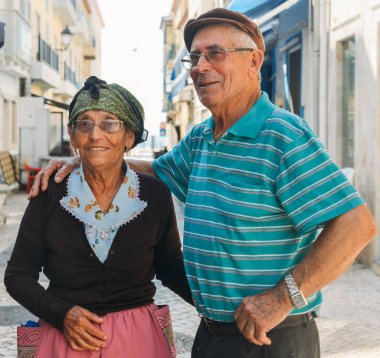 Geleneksel olarak yaşlı Portekizli kadın ve kocası Nazare, Portekiz bir Arnavut kaldırımlı sokakta giyinmiş