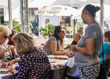 Gypsie kadın, Doğu Avrupa'dan büyük olasılıkla bozuk para için bir restoranda oturan turist yalvarıyor