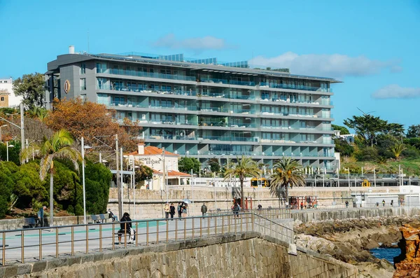 Train arriving at Cascais railway station, 30km west of Lisbon, Portugal. View of people strolling on seawalk adjacent to train tracks — Stock Photo, Image