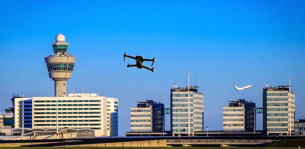 Unmanned drone flying near airport with air traffic control tower, flight disruption concept - digital composite — Stock Photo, Image