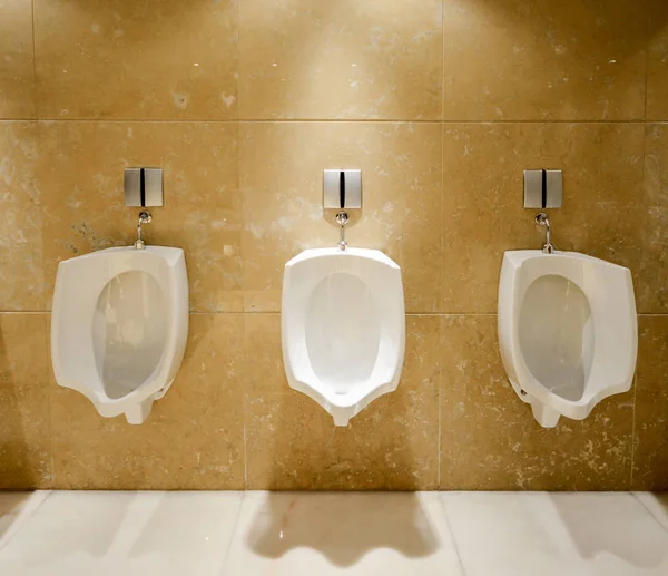Una fila de urinarios en la pared de baldosas en un baño público —  Fotos de Stock