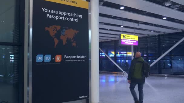Passagiers wandelingen verleden teken vóór de immigratie paspoortcontrole op de luchthaven van Heathrow, Londen - Brexit thema — Stockvideo