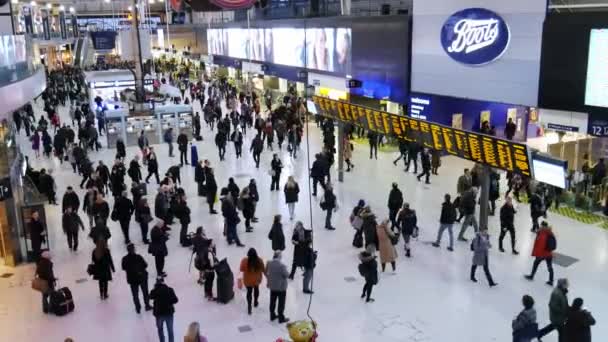 Mucha gente delante de la exhibición digital del horario en la hora punta en la estación de tren de Waterloo, Londres - 4K — Vídeos de Stock