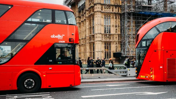 Armed to the teeth two police officers provide security on Westminster Bridge, London framed by two double-decker red buses — Stock Photo, Image